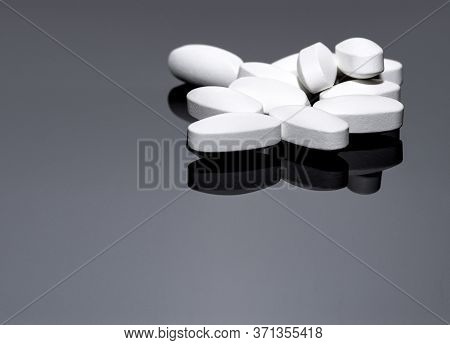 White Tablets On A Glossy Background With Reflection