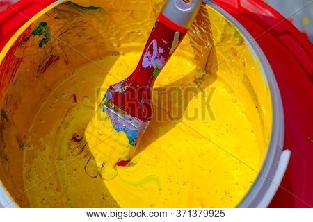 A Jar Of Old Yellow Paint With A Dirty Brush In It .can Of Yellow Paint And Brush. Top View