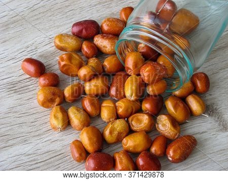 Organic Dried Fruit Of Oleaster Scattered From A Glass Bottle On Wooden Table. Fresh Fruit Of The Ol