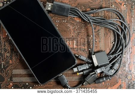 Smartphone With Universal Charging Cable. Against The Background Of An Electronic Circuit Board.