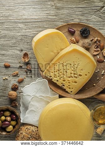 Assortment Of Cheeses, Wine, Nuts And Fruits On A Wooden Table. Top View. Free Space For Text.
