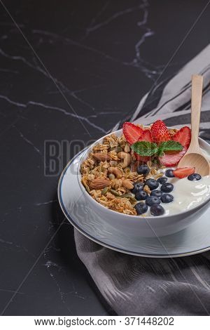 Bowl Of Homemade Granola Yogurt With Fresh Berries On Black Table For Breakfas