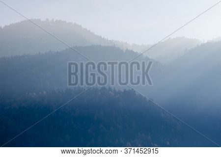Beautiful tranquil landscape from blurred foggy mountains with trees on a background of sunny clear sky in Kufstein Austria.