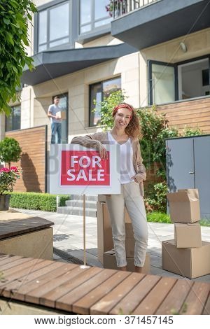 Smiling Young Woman Standing With A Table For Sale And Feeeling Good