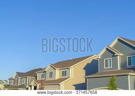 Homes With Horizontal Wall Sidings And Front Gable Roofs Againts Clear Blue Sky