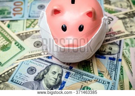 Piggy Bank In A Mask On A Background Of American Currency.the Concept Of Coronavrius Epidemic