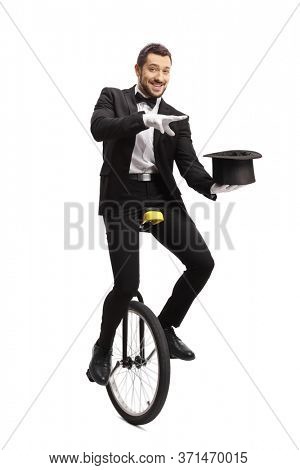 Magician riding a mono-cycle and performing a magic trick with a hat isolated on white background