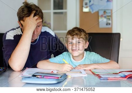 Cute Little School Kid Boy At Home Making Homework With Dad. Child Writing, Father Helping Him, Duri