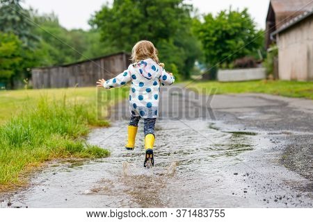 Little Toddler Girl Wearing Yellow Rain Boots, Running And Walking During Sleet On Rainy Cloudy Day.