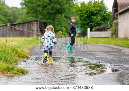 Two Children, Toddler Girl And Kid Boy Wearing Red And Yellow Rain Boots, Walking During Sleet. Happ