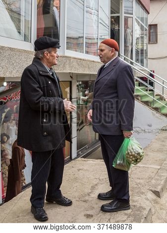 Gnjilane, Gjilan - January 2, 2016: Old Aged Retired Men, One Wearing A Traditional Hat, Discussing 