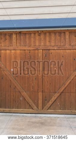 Vertical Crop Brown Wood Garage Door With Blue Frame Flaned By Wall Mounted Vintage Lanterns