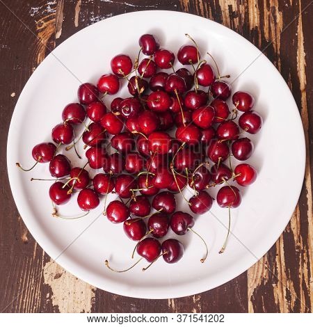 Top View Of A Lot Of Fresh Sweet Cherry Fruit Berries With Water Drops. Close-up On The Plate On Woo