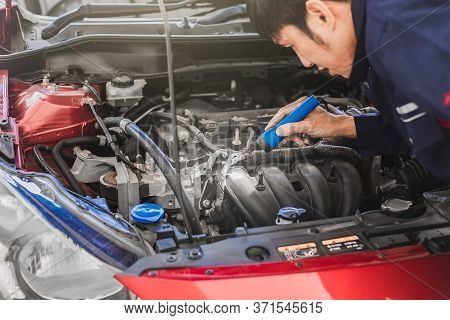 Man Mechanic Inspection Shine A Torch Car Engine Checking Bug In Engine From Application Smartphone.