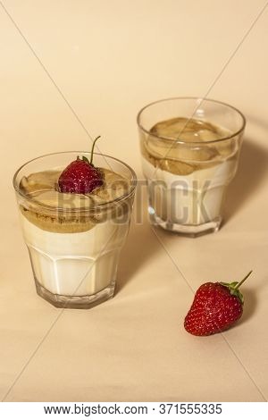 Dalgon Coffee In A Transparent Glass With Milk On A Pastel Background With Strawberries.