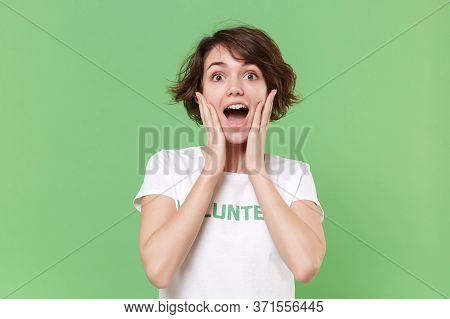 Surprised Young Brunette Woman In White Volunteer T-shirt Isolated On Pastel Green Background Studio