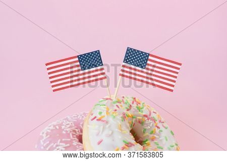 Two mini american flags of toothstick stuck top in donuts on pink background. 4th of july, happy usa independence day. Celebration memorial day in America. Copy space for text.