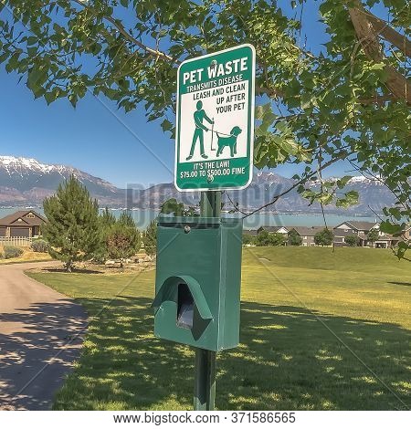 Square Frame Pet Waste Station With Dog Poop Bags And Garbage Can Beside A Tree And Pathway