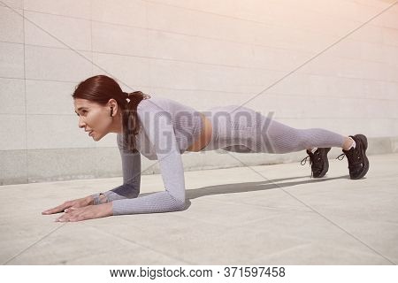 Young Woman Doing Fitness With Earplugs Outdoors Soft Sun Lights