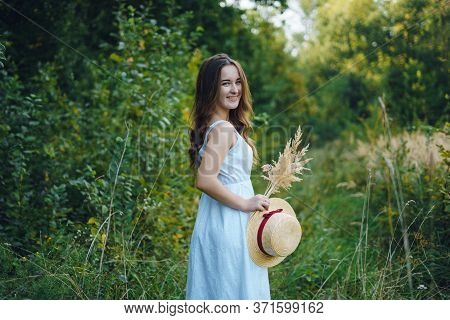 Beautiful Girl In A White Dress With A Bouquet Of Dried Flowers. Young Woman In A Green Park. Girl I