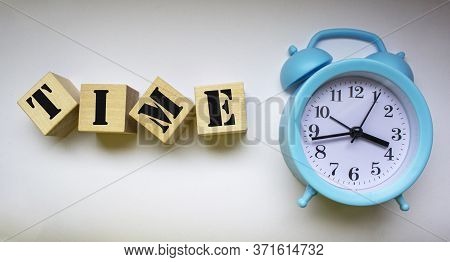 Close-up Of An Alarm Clock Near Wooden Blocks With The Text Time