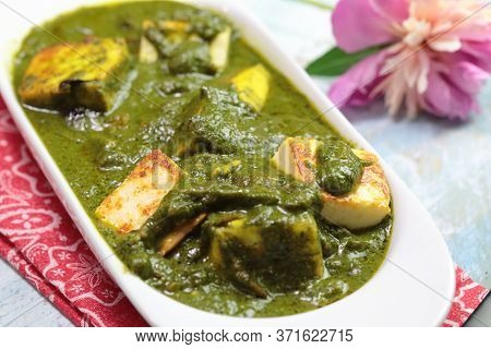 A Bowl Of Palak Paneer Made Of Paneer Cheese Dipped In Mildly Spiced Spinach Gravy On Wooden Backgro