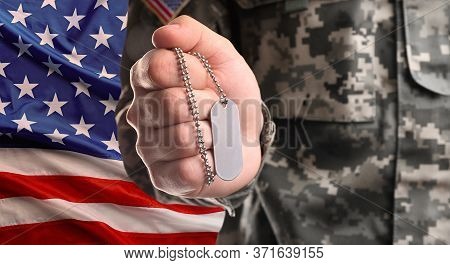 Male Soldier Holding Military Id Tag And American Flag On Background, Closeup. Military Service