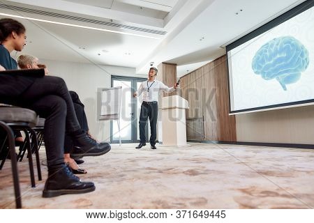 Full-length Shot Of Asian Male Speaker In Suit Giving A Talk At Corporate Business Meeting, Forum. A