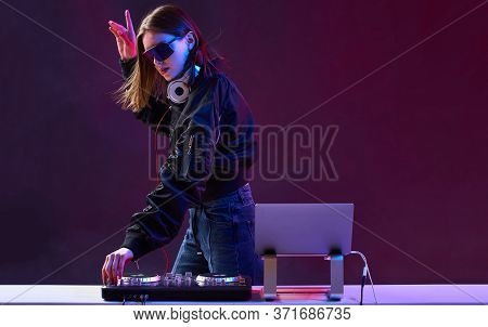 Stylish Dj Girl With Headphones And Glasses On The Bomber Jacket Mixes The Music At The Party And Ne