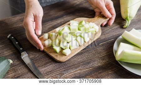 Zucchini Harvest. Woman Slices Zucchini Cubes For Freezing On Wooden Table. Farm Organic Zucchini Ha
