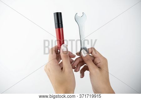 Womans Hands Holding Lip Gloss In One Hand And Wrench In Another On Isolated White Background, Beaut