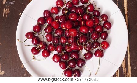 Top View Of A Lot Of Fresh Sweet Cherry Fruit Berries With Water Drops. Close-up On The Plate On Woo