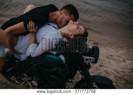 Couple Makes Love On Beach Lying On Motorcycle On Water Background. Closeup.