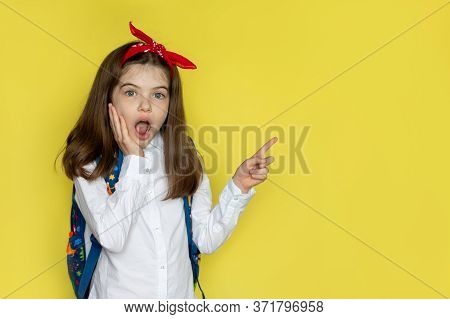 Little Beautiful School Girl In A School Uniform With A Backpack Surprised, Opened Her Mouth. Advert