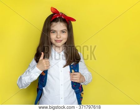 Little Beautiful School Girl In A School Uniform With A Backpack Raised A Finger Up. Advertising Con