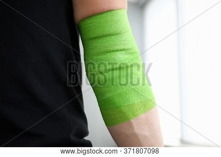 Close-up Of Athlete With Sore Hand In Swathe Wrap. Male Person Wearing Green Elastic Bandage. Sports