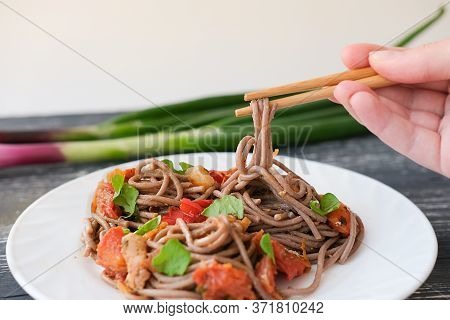Girls Hand Holding Soba Buckwheat Noodles On Chopsticks. Fresh Soba On White Plate With Chicken And 