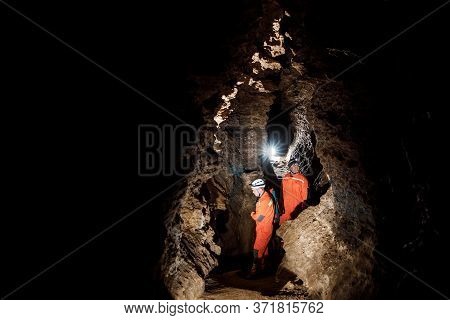 Two Men, Strong Physique, Explore The Cave. Men Dressed In Special Clothes To Pass Through The Cave 