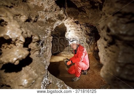 Man Walking And Exploring Dark Cave With Light Headlamp Underground.