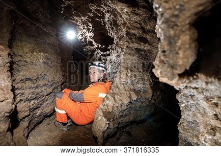Man Walking And Exploring Dark Cave With Light Headlamp Underground.
