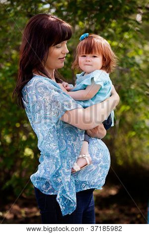 ภาพเหมือนของแม่ตั้งครรภ์ในไตรมาสที่สามพร้อมกับลูกสาวในสวน