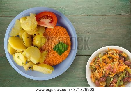 Meatball With Potatoes On Green Wooden Background. Meatball With A Slice Of Tomato On Light Blue Pla