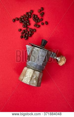 Flat Lay Of Coffee Maker And Coffee Beans On Red Background.