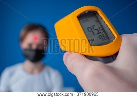 Measurement, Healthcare, Infection, Coronavirus Concept. Man Hand Holding Yellow Pyrometer And Measu