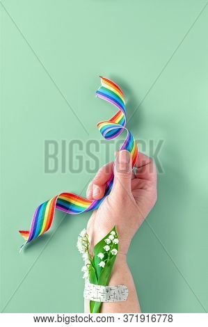 Rainbow Ribbon In Hand. Lily Of The Valley Flowers, Small Bouquet Attached To Wrist With Medical Pat