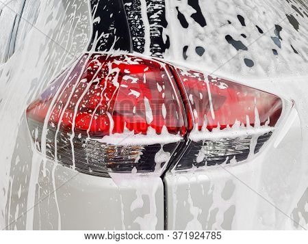 Car Taillight On Back Lid Covered With Active Foam For Washing A Dirty Car And  Wax, Close Up Of The