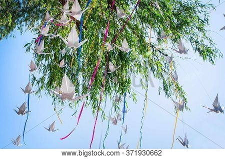 The Tree Is Decorated With Paper Cranes And Colored Ribbons. Origami For Decorating Outdoor Events