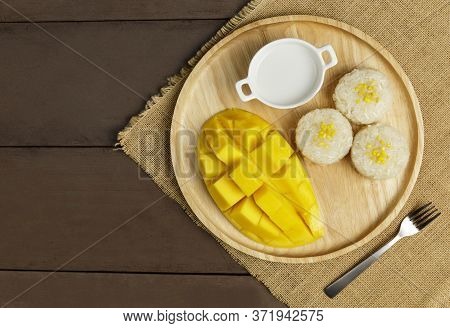 Top View Yellow Half  Mango With Small Fork. Mango Fruit Cubes On The Wooden Table. Tropical Fruit A