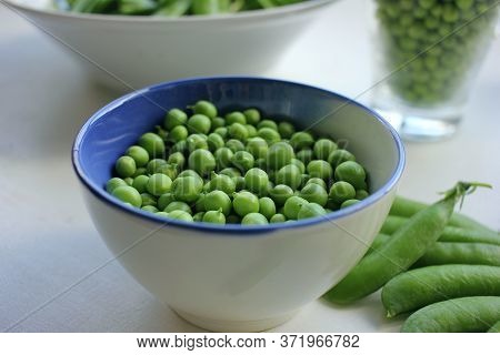 Fresh Peeled Green Sugar Snap Peas In A Bowl And Open Pods On A White Wooden Table Background With C
