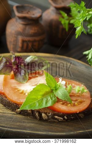 Dark Bread Bruschetta With Red Tomatoes And Green Basil Leaves Close Up On A Wooden Textured Rustic 